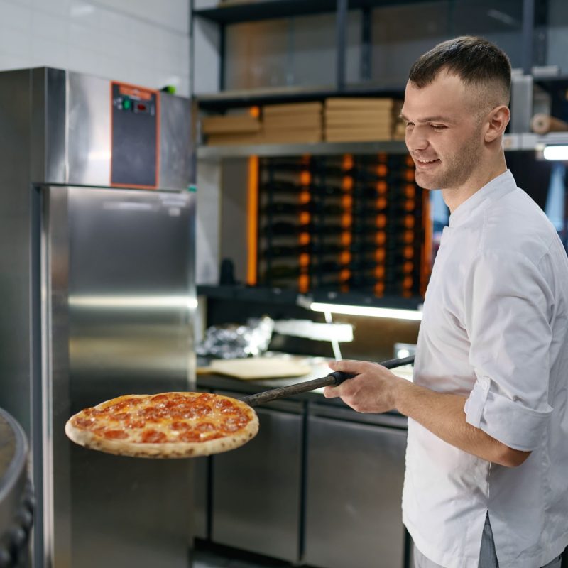 cheerful-young-man-working-in-pizza-shop-presentin-2023-11-27-05-33-56-utc